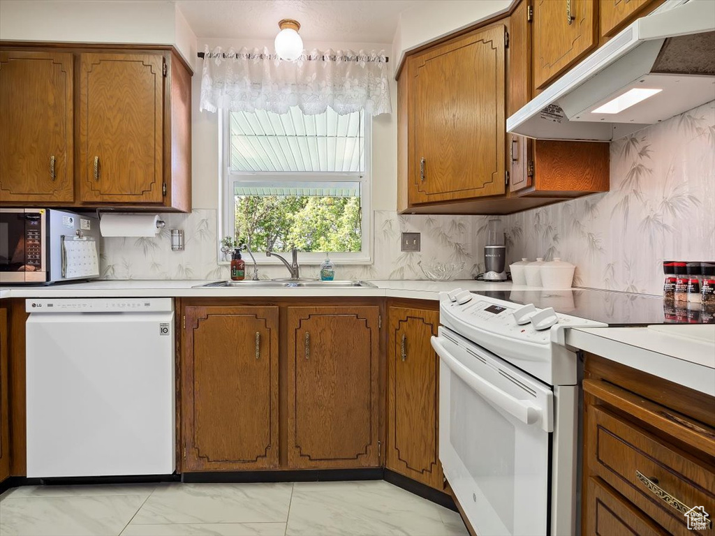 Kitchen featuring sink, white appliances, backsplash, and light tile floors