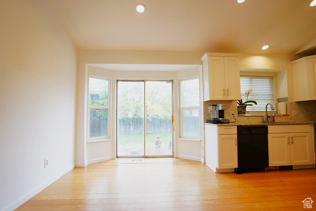 Kitchen featuring a healthy amount of sunlight, tasteful backsplash, light hardwood / wood-style floors, and dishwasher