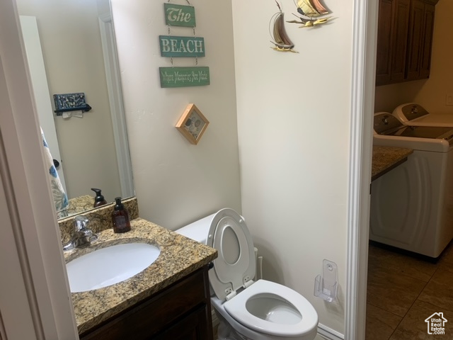 Bathroom with toilet, tile flooring, vanity, and separate washer and dryer