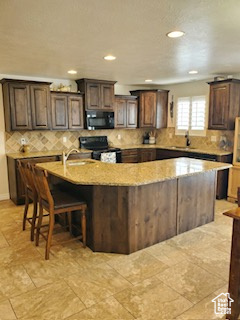 Kitchen with light tile flooring, a kitchen island with sink, and a breakfast bar