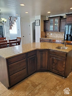 Kitchen featuring dark brown cabinets, tasteful backsplash, sink, and light tile floors