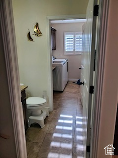 Bathroom with vanity, toilet, tile flooring, and washing machine and dryer