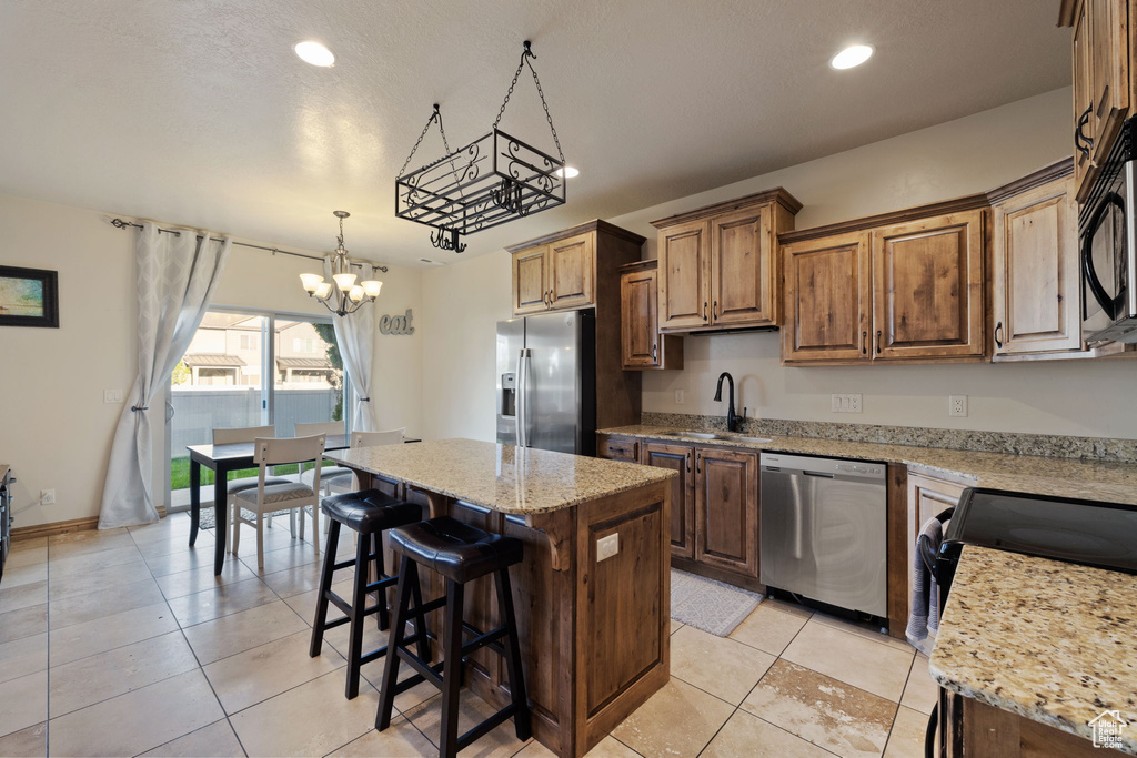 Kitchen featuring stainless steel appliances, a notable chandelier, light tile floors, a kitchen island, and sink