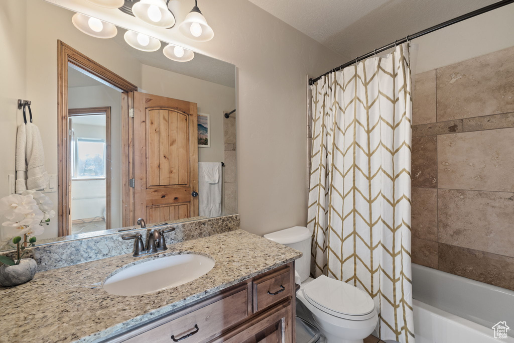 Full bathroom featuring vanity with extensive cabinet space, an inviting chandelier, toilet, and shower / bath combo