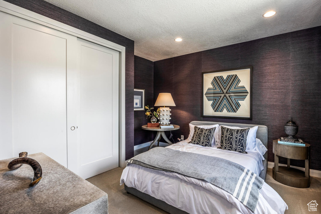 Bedroom with a closet, a textured ceiling, and dark carpet