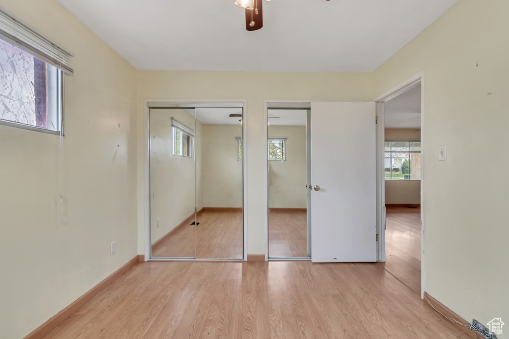 Unfurnished bedroom featuring light hardwood / wood-style floors, ceiling fan, and two closets