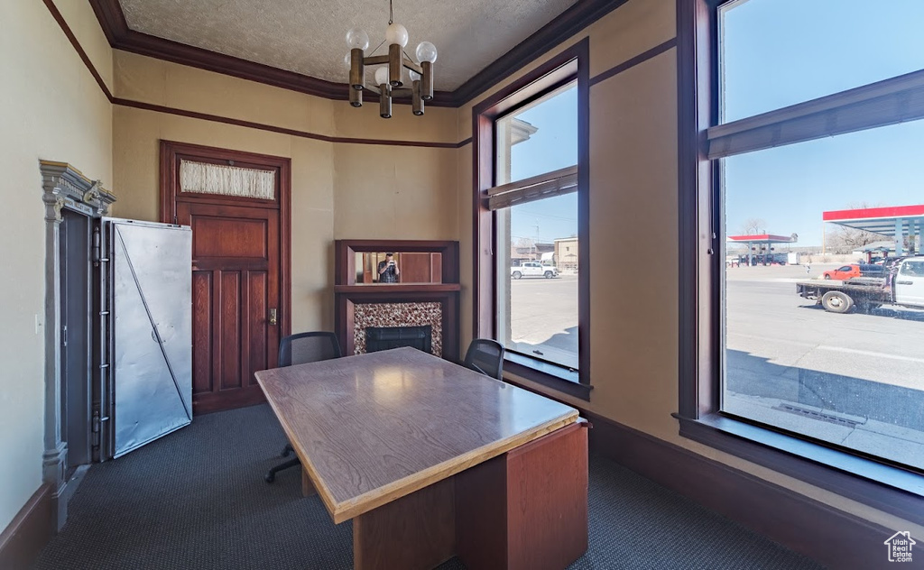 Unfurnished office with ornamental molding, an inviting chandelier, a healthy amount of sunlight, and dark colored carpet