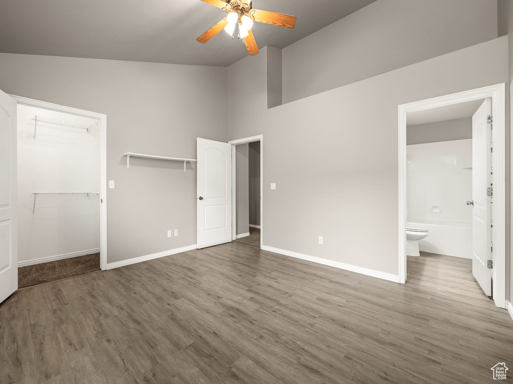 Unfurnished bedroom with a closet, ensuite bath, hardwood / wood-style flooring, ceiling fan, and lofted ceiling