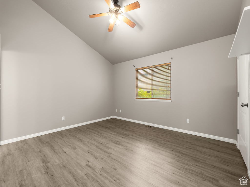 Empty room with ceiling fan, hardwood / wood-style floors, and lofted ceiling