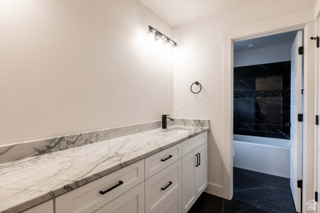 Bathroom with tile flooring, tiled shower / bath, and vanity