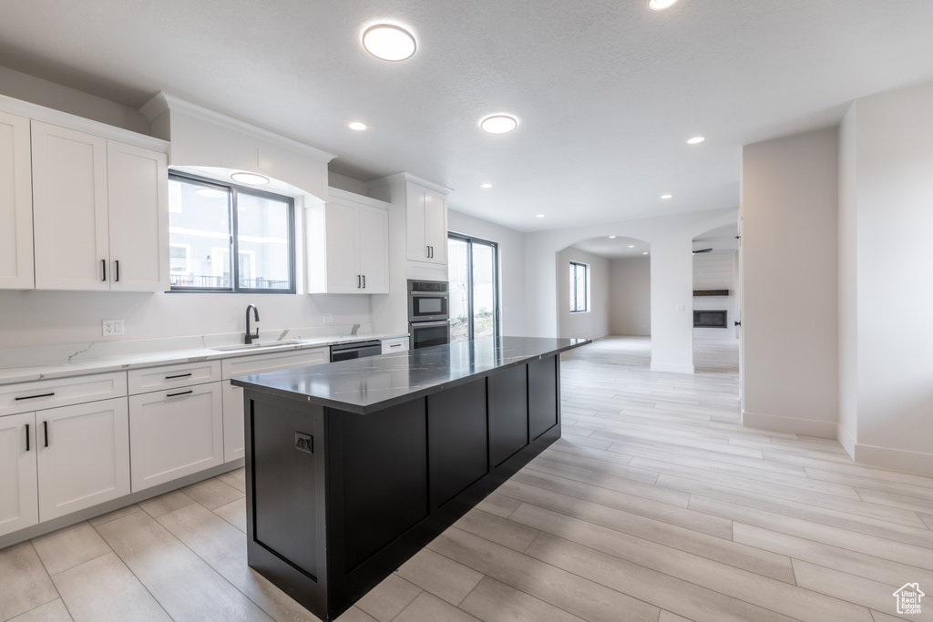 Kitchen featuring a center island, white cabinets, light hardwood / wood-style flooring, appliances with stainless steel finishes, and sink
