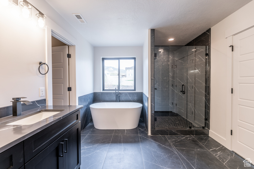 Bathroom featuring a textured ceiling, plus walk in shower, vanity, and tile floors