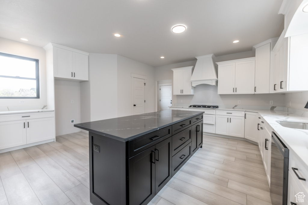Kitchen with premium range hood, a center island, dishwasher, and white cabinets