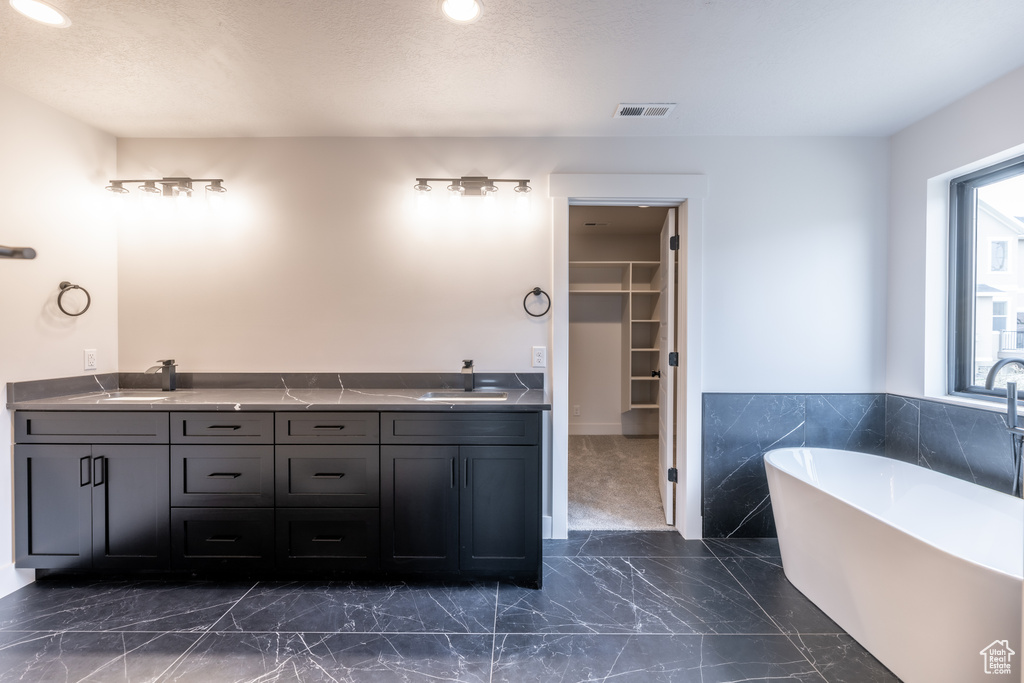 Bathroom with tile floors, oversized vanity, double sink, and a bathing tub