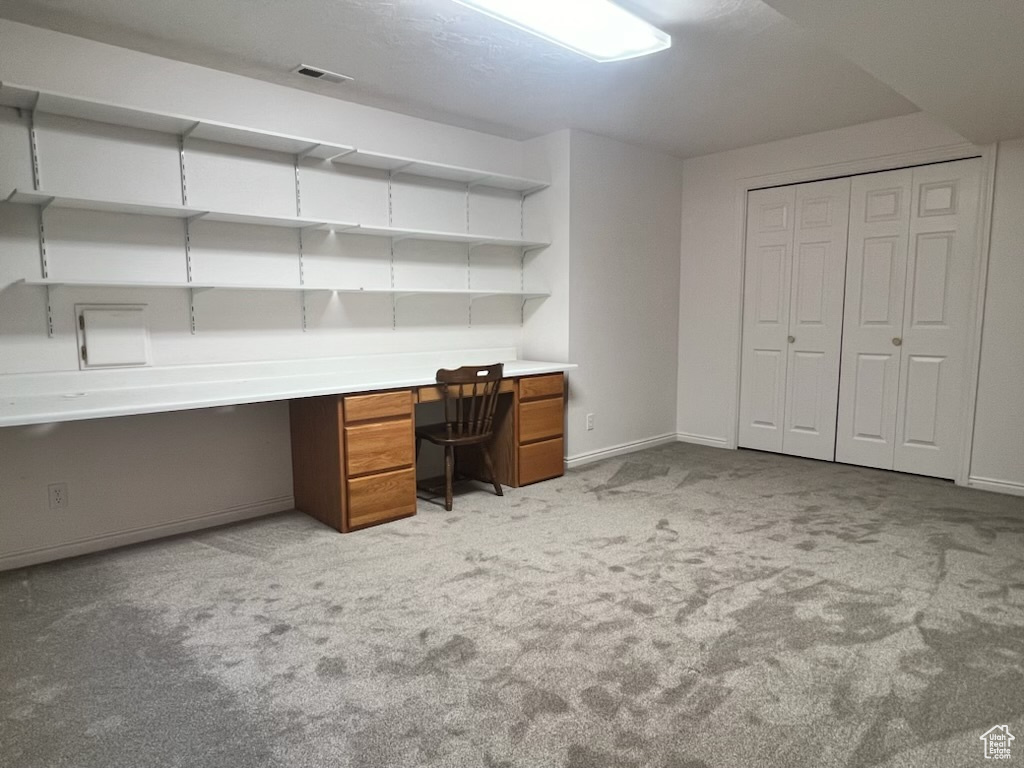Unfurnished office featuring built in desk and carpet floors