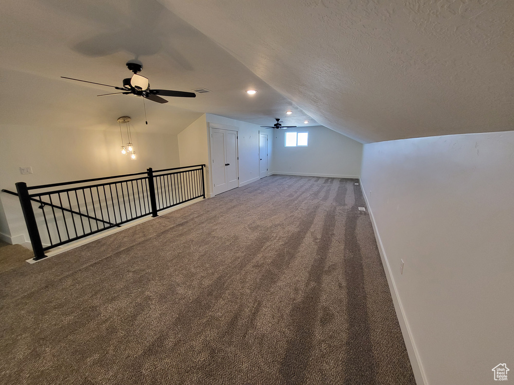 Bonus room with lofted ceiling, ceiling fan, carpet, and a textured ceiling