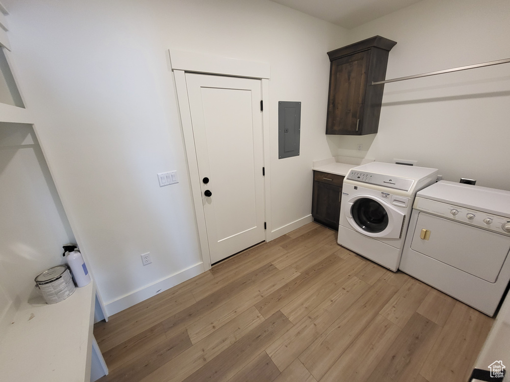 Clothes washing area featuring light hardwood / wood-style floors, separate washer and dryer, and cabinets
