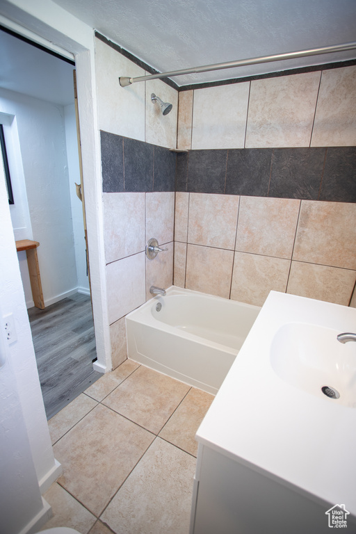 Bathroom with hardwood / wood-style floors, tiled shower / bath, and vanity