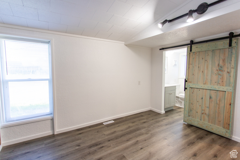 Spare room featuring dark hardwood / wood-style floors, lofted ceiling, and a barn door