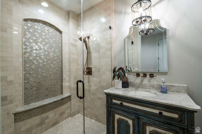 Bathroom with vanity with extensive cabinet space, a shower with door, and an inviting chandelier