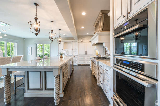 Kitchen featuring a large island, pendant lighting, dark hardwood / wood-style flooring, a kitchen bar, and white cabinetry
