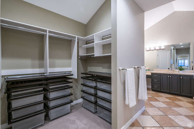 Spacious closet with high vaulted ceiling, sink, and light tile flooring
