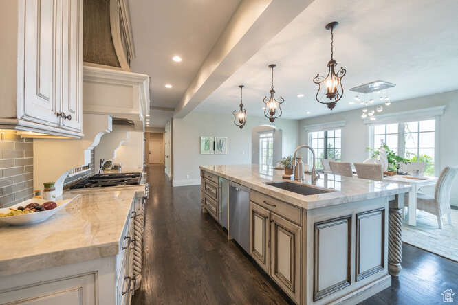 Kitchen featuring dark hardwood / wood-style floors, a kitchen island with sink, pendant lighting, sink, and stainless steel dishwasher