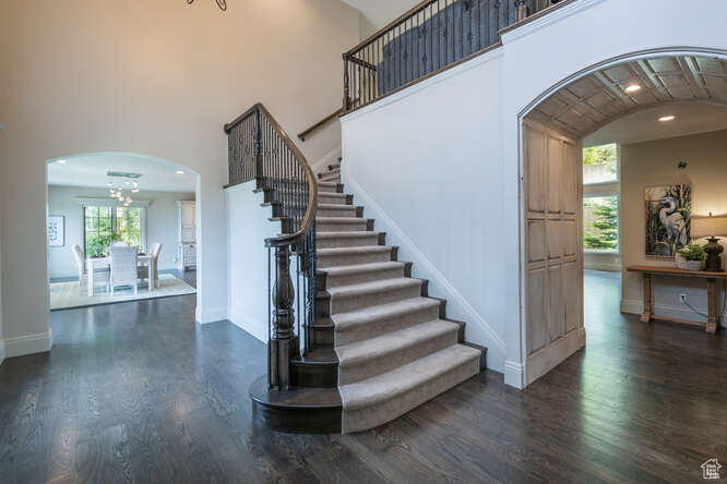 Stairway featuring a chandelier, dark wood-type flooring, and a towering ceiling