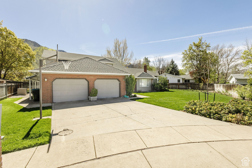 Ranch-style home featuring a garage and a front lawn