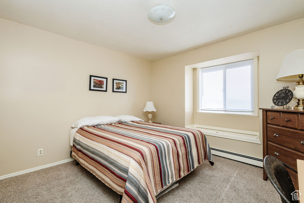 Carpeted bedroom with a baseboard heating unit