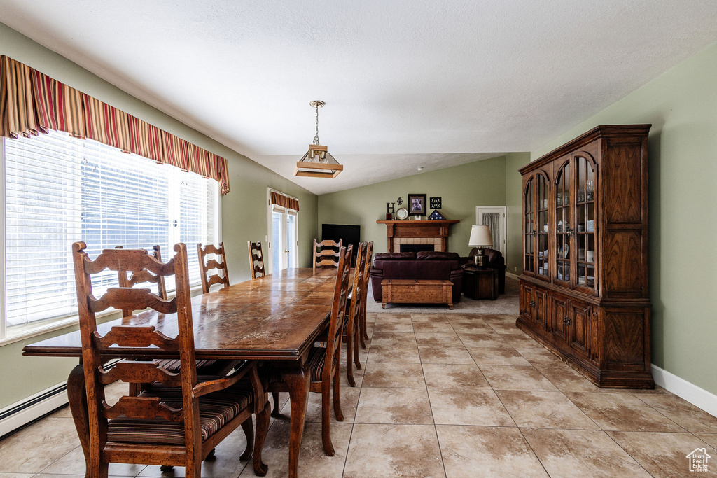 Tiled dining room with lofted ceiling and a baseboard heating unit