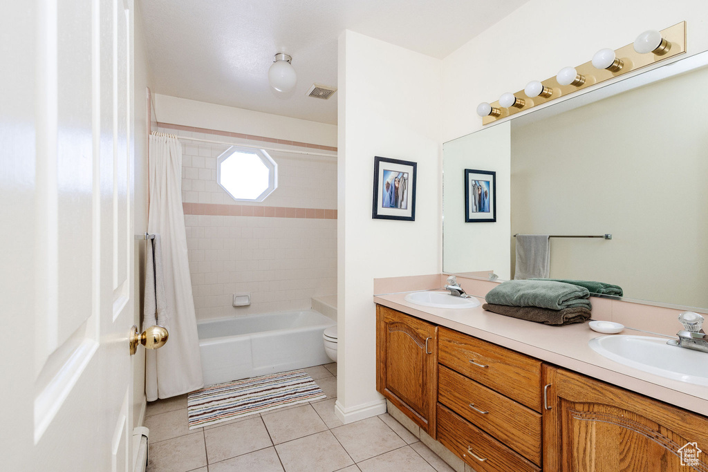 Full bathroom featuring shower / tub combo, toilet, double vanity, and tile flooring