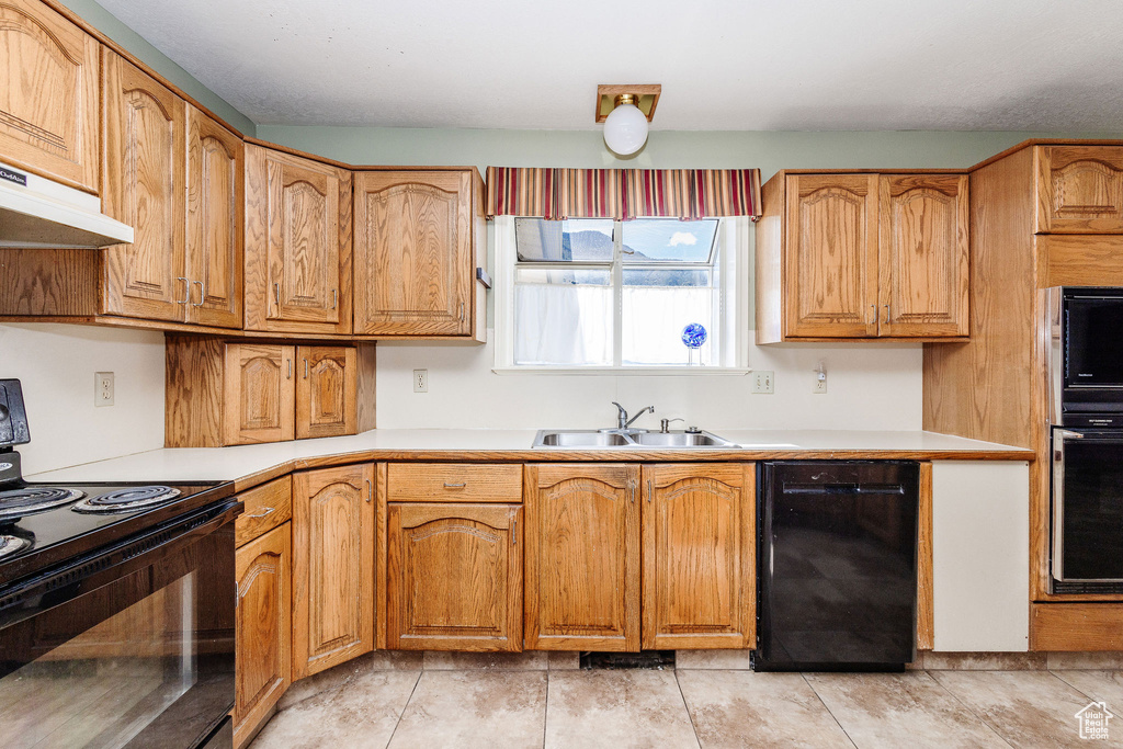 Kitchen with light tile floors, black appliances, and sink