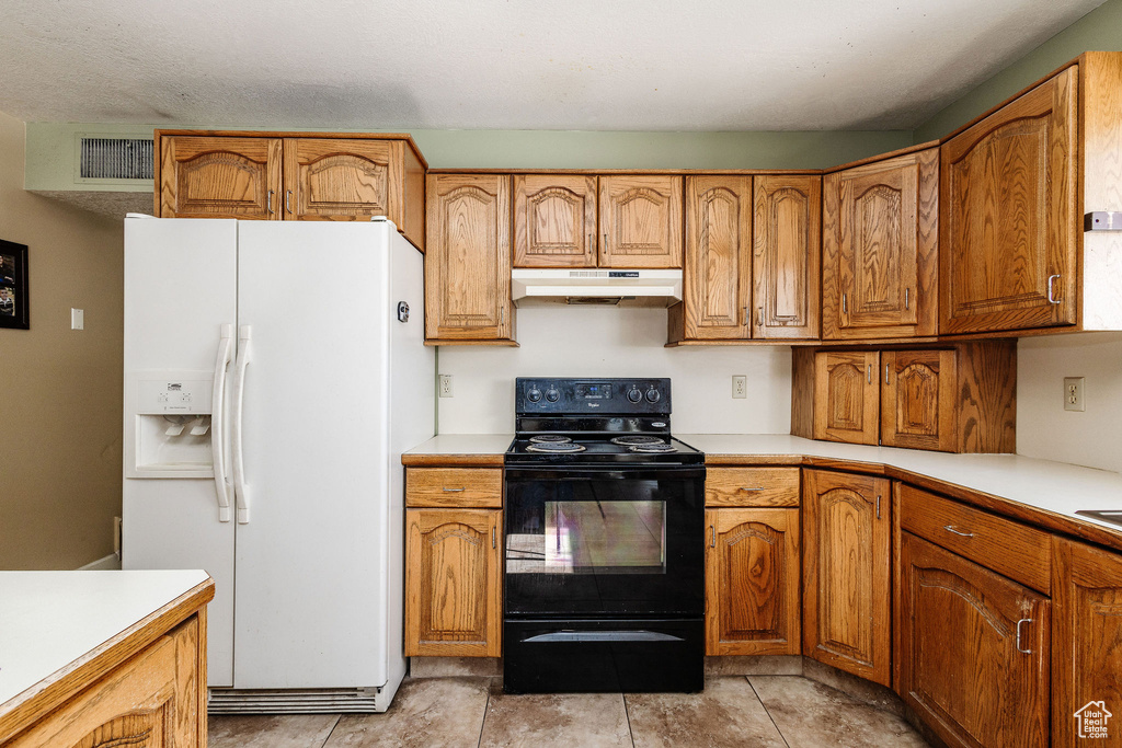 Kitchen with white refrigerator with ice dispenser, light tile floors, and black electric range