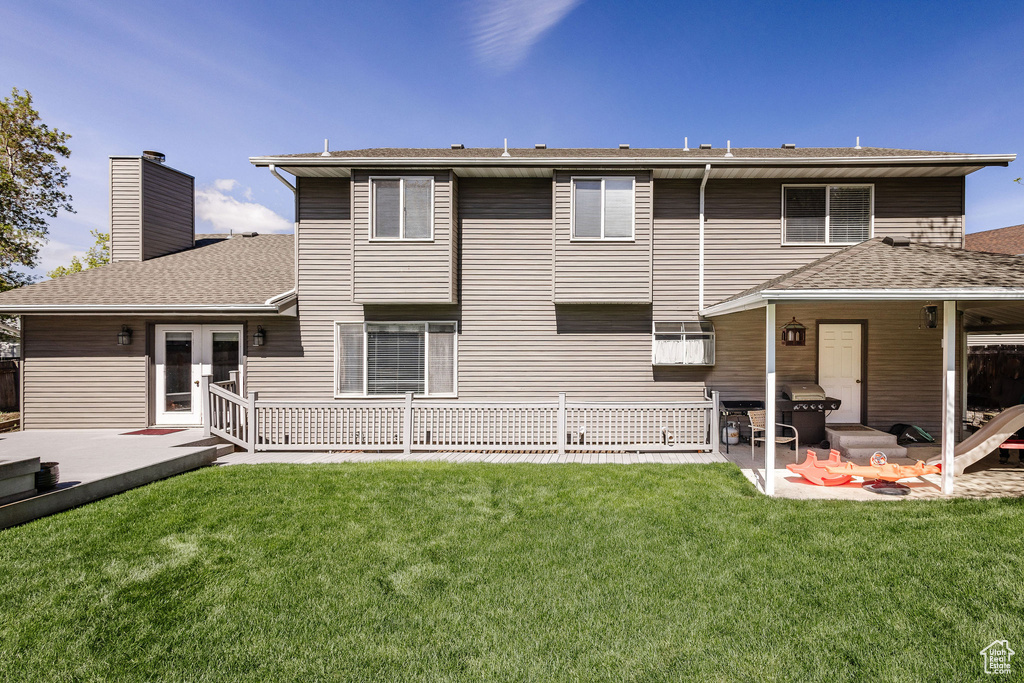 Back of property with a lawn and a patio