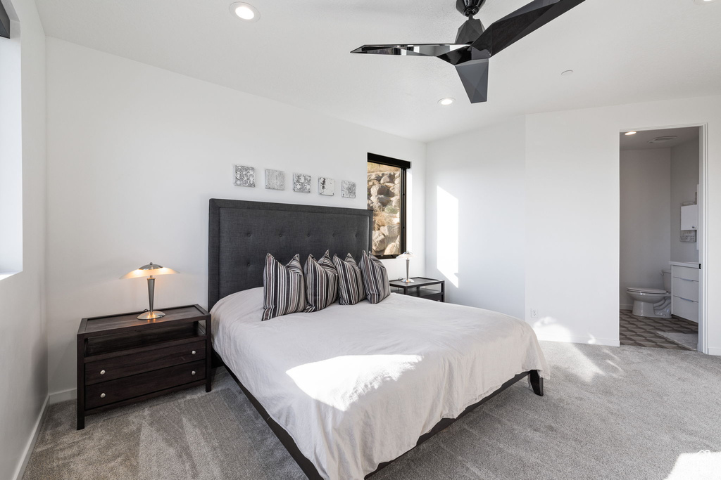 Bedroom featuring ceiling fan, carpet floors, and ensuite bathroom