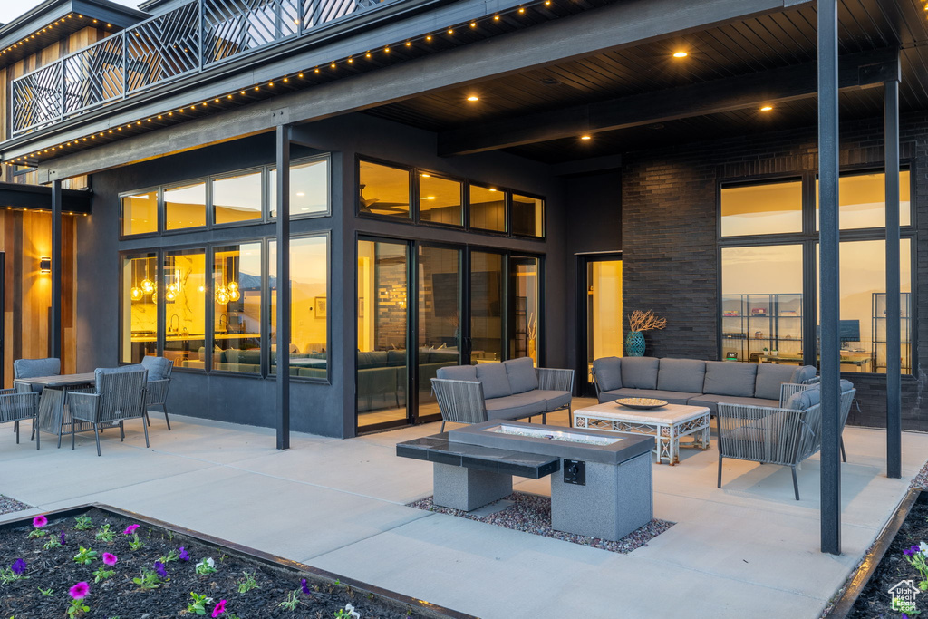 Patio terrace at dusk with a balcony and an outdoor living space with a fire pit