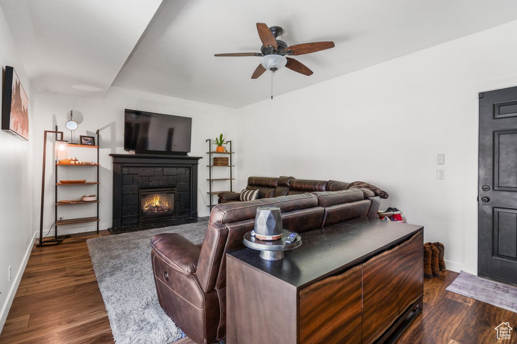 Living room featuring ceiling fan, a fireplace, and dark wood-type flooring