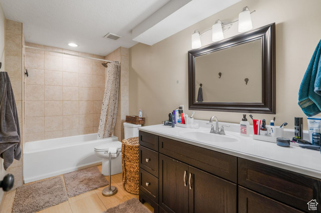 Full bathroom with large vanity, tile floors, toilet, and shower / bath combo with shower curtain
