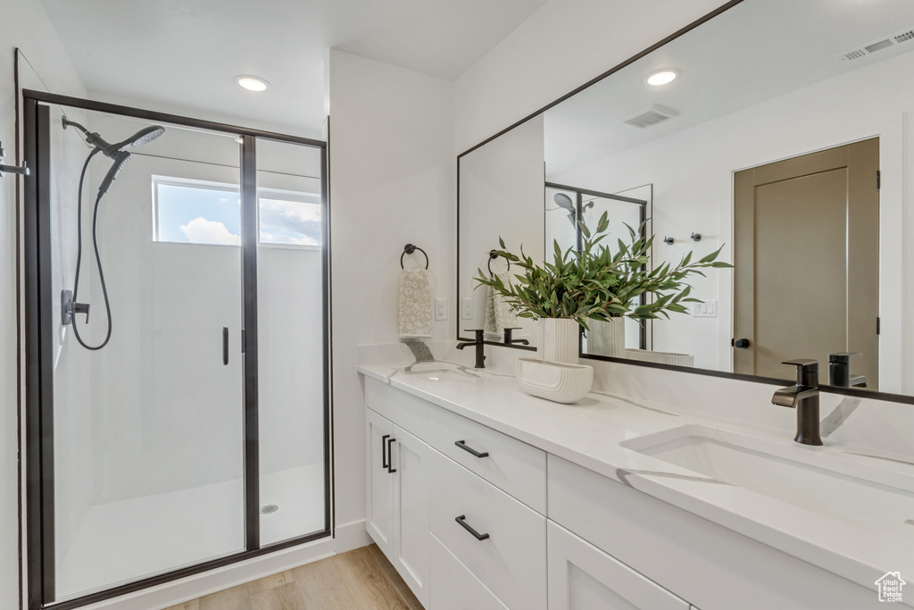 Bathroom with walk in shower, wood-type flooring, and double sink vanity