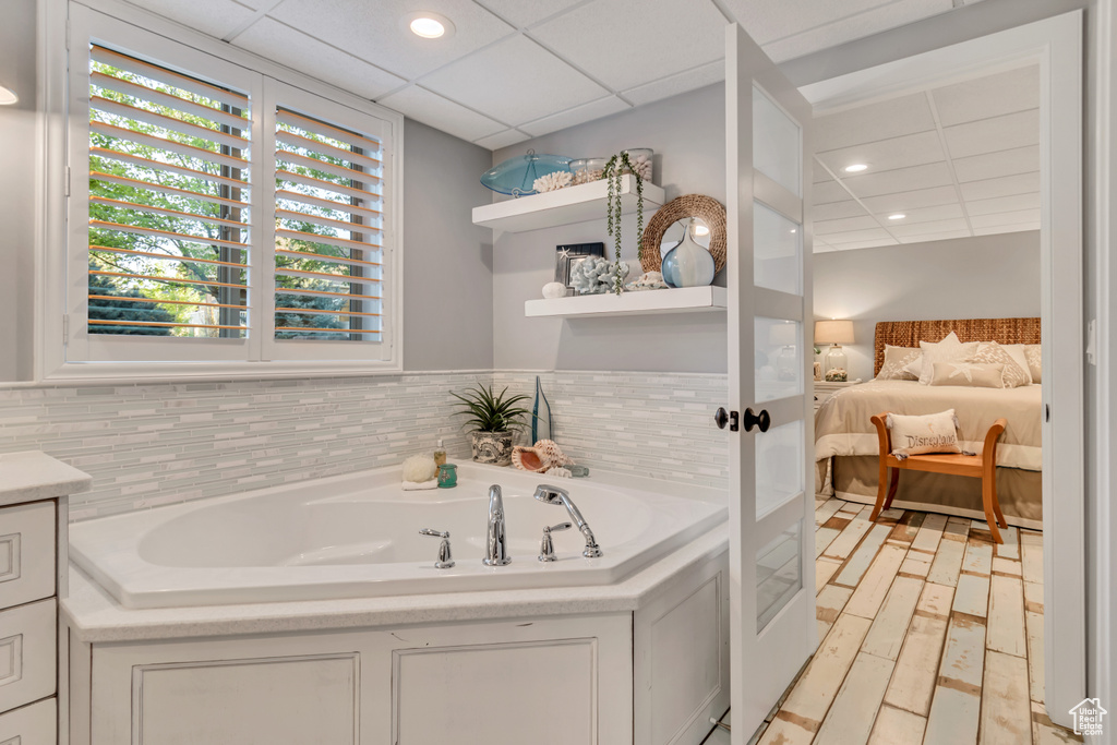 Bathroom featuring vanity, a paneled ceiling, and a bath