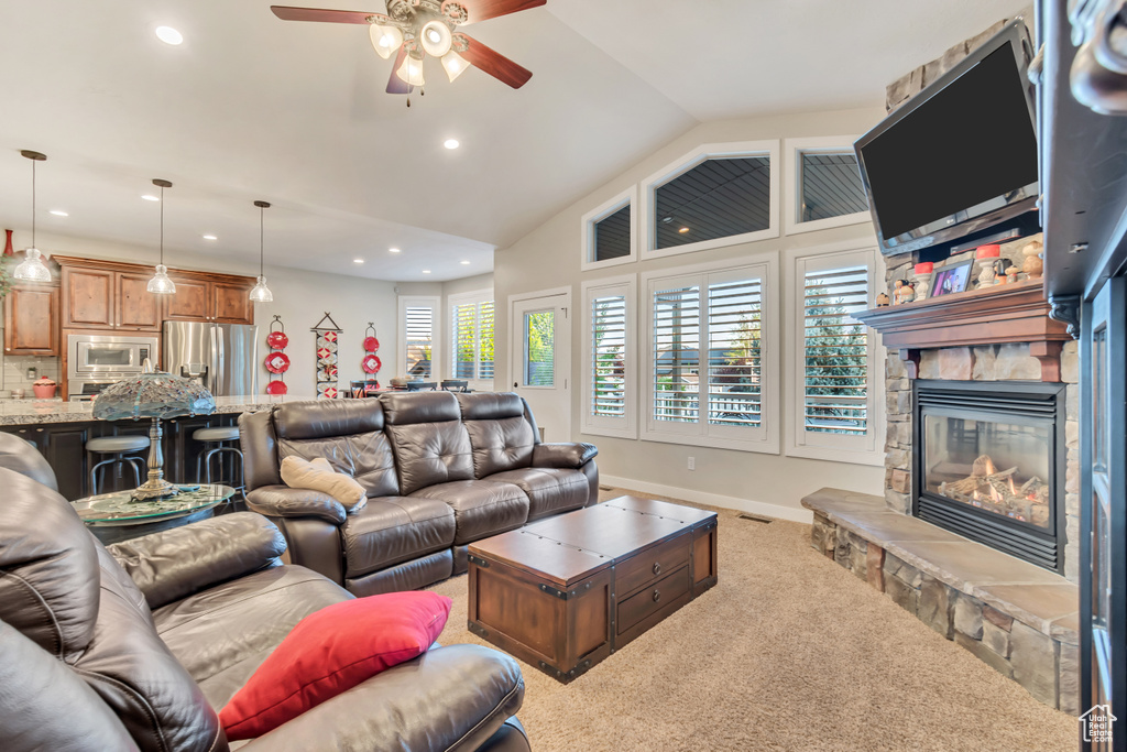 Carpeted living room featuring a fireplace, ceiling fan, and lofted ceiling