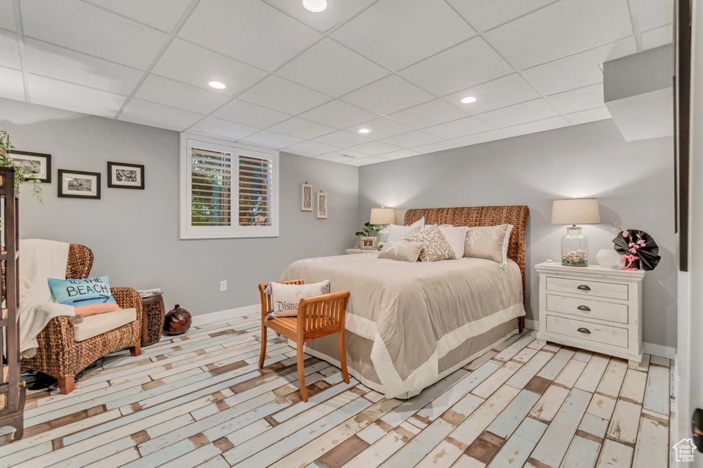 Bedroom with a drop ceiling and light hardwood / wood-style flooring
