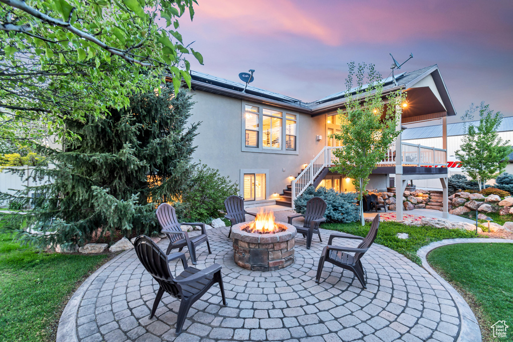 Back house at dusk with a patio area and a fire pit