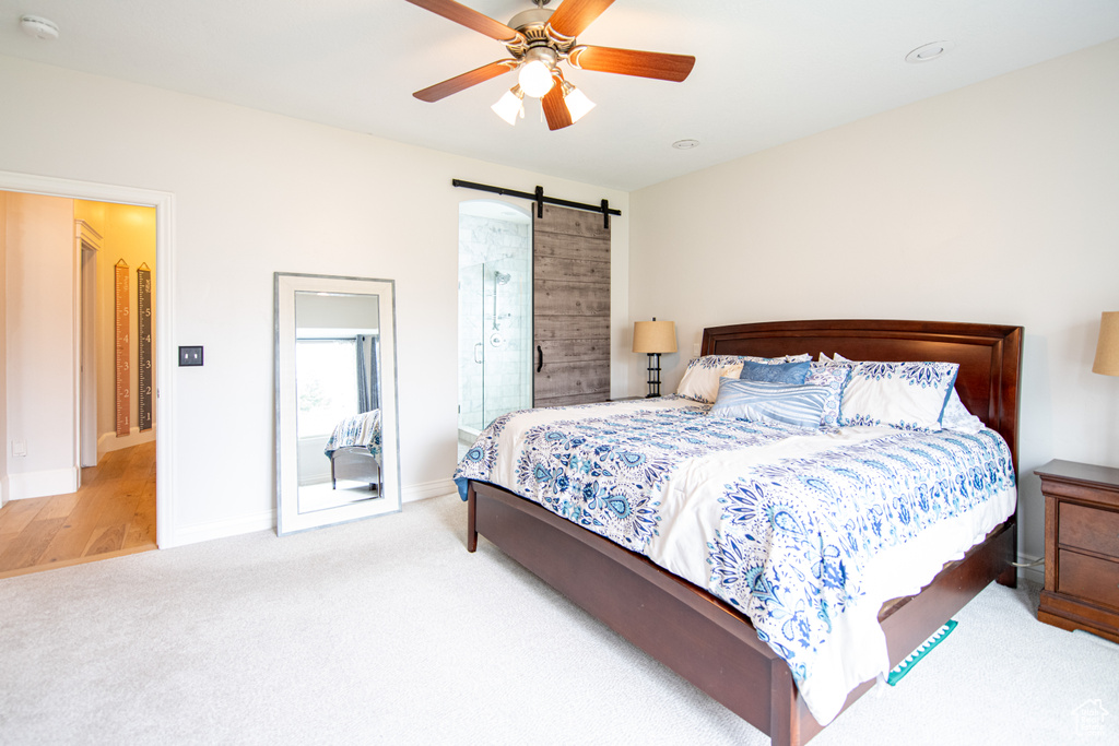 Carpeted bedroom featuring ceiling fan and a barn door