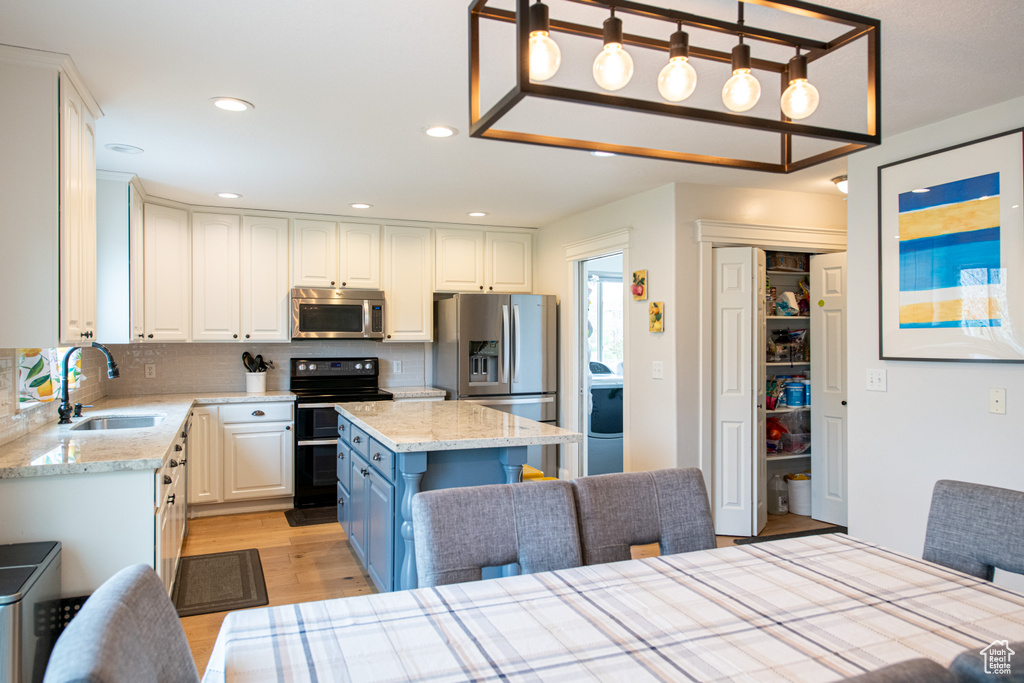Kitchen with a center island, light hardwood / wood-style flooring, stainless steel appliances, sink, and tasteful backsplash