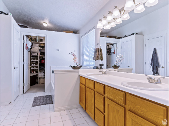 Bathroom featuring tile flooring, dual vanity, and a textured ceiling