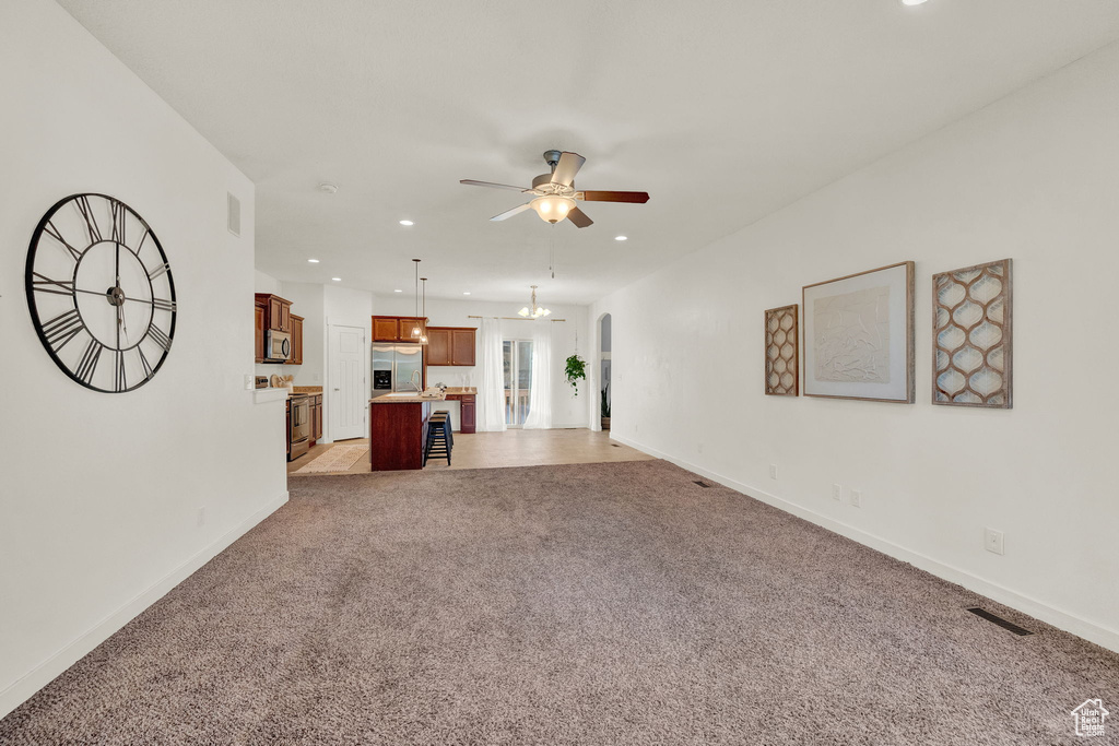 Unfurnished living room with light carpet and ceiling fan