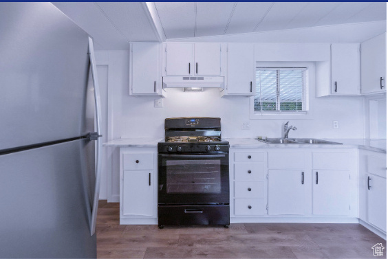 Kitchen featuring white cabinetry, sink, hardwood / wood-style flooring, electric range, and stainless steel fridge