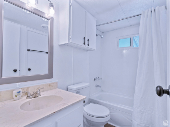 Full bathroom featuring large vanity, toilet, and shower / bath combo with shower curtain